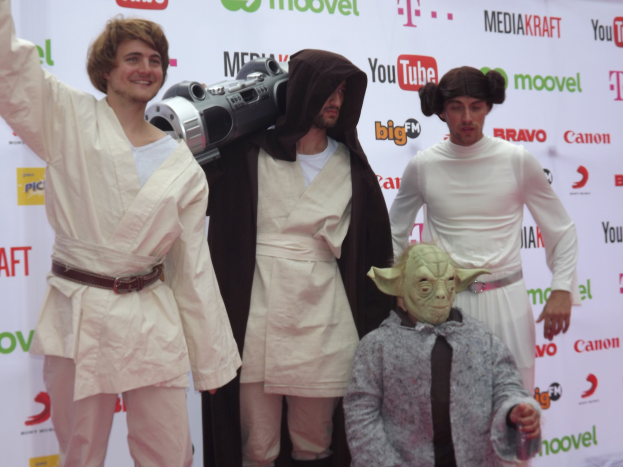 Gruppe von Menschen in Star-Wars-Kostümen auf einem roten Teppich mit einem Banner im Hintergrund.