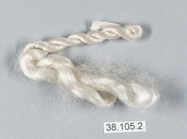 Ein Faden weißer Seidenfaden auf einer grauen Oberfläche mit einer Zahl darauf.