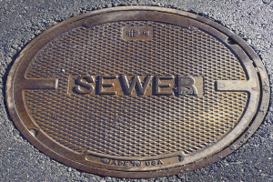 Metall-Schachtobjekt auf der Straße mit dem Wort "Kanal" eingraviert.