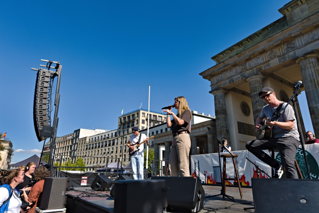 Eine Gruppe von Menschen, die auf einer Bühne vor dem Brandenburger Tor in Berlin spielt und singt.