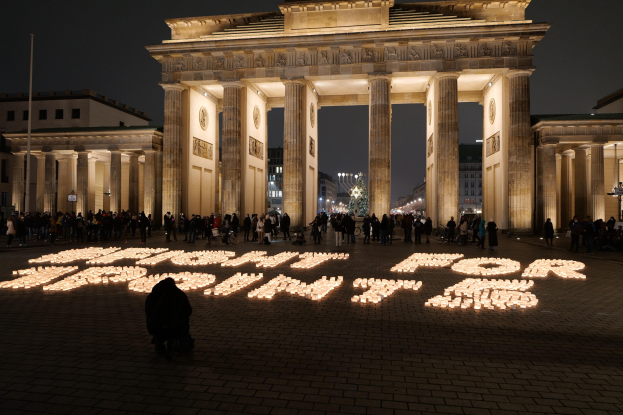 Eine Gruppe von Menschen steht vor dem beleuchteten Brandenburger Tor in Berlin, Deutschland, mit der Aufschrift "Kampf für die Freiheit" im Vordergrund.