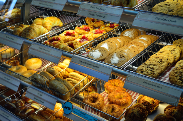 Eine Vitrine voller verschiedener Kuchen, Torten, Plätzchen und anderen Backwaren, mit Schildern, die die Art der Backwaren angeben.