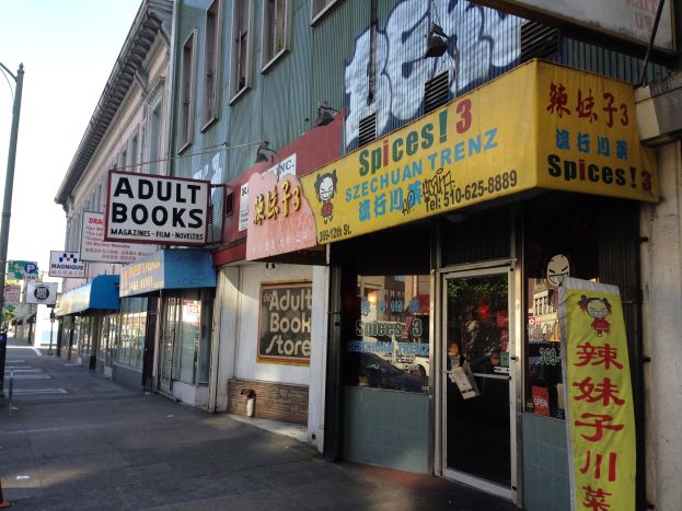 Eine belebte Stadtstraße mit Gebäuden, Geschäften, Schildern, Polen, Laternen, Verkehrskegeln, Fahrzeugen, Bäumen und einem klaren Himmel, mit einem Schaufenster in der Mitte, auf dem "Erwachsenenbücher" steht.