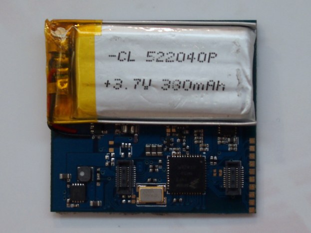 Nahaufnahme einer Handy-Batterie auf einer Platine, die auf einer weißen Oberfläche mit gedrucktem Text zu sehen ist.