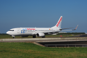Ein Air Europa Airbus A320-200 auf dem Rollfeld am Frankfurter Flughafen, umgeben von Gras und einem Geländer, mit Bäumen, Gebäuden und einem klaren blauen Himmel im Hintergrund.