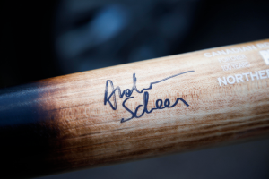 Ein Nahaufnahme eines hölzernen Hockey-Schlägers mit einer Signatur und Text darauf.