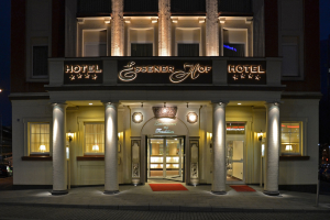 Das Essenerhof Hotel in Berlin, Deutschland, ein mehrstöckiges Gebäude mit Fenstern, Türen, Säulen und einem Namensschild, das auf einer Straße mit Fahrzeugen rechts und einem klaren Himmel im Hintergrund steht.