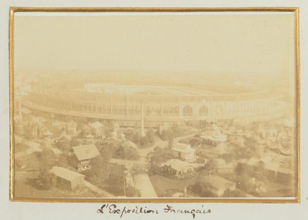 Altes Schwarz-Wei├č-Foto eines Stadions, umgeben von Geb├Ąuden, B├Ąumen und Masten, mit Text unten.