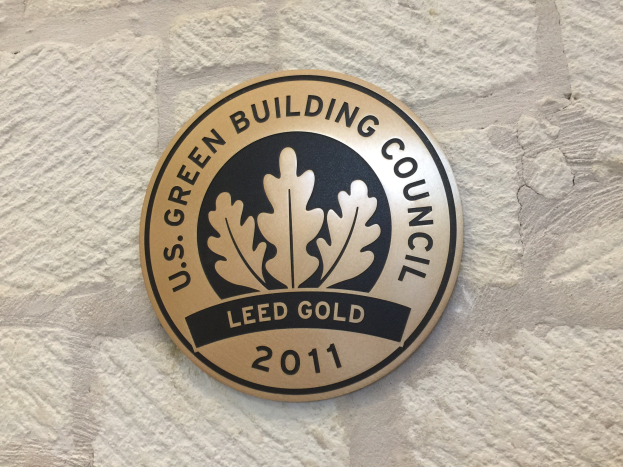Logo der U.S. Green Building Council an der Außenseite eines Gebäudes, mit einem grünen Schild mit weißer Umrandung, fetter schwarzer Schrift und einem umgebenden Lorbeerkranz.