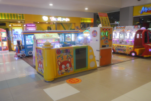 Ein geräumiger Arcade-Raum mit verschiedenen Arten von Arcade-Automaten, einer beleuchteten Decke und einer Hintergrundwand, der eine Vergnügungspark-Atmosphäre schafft.