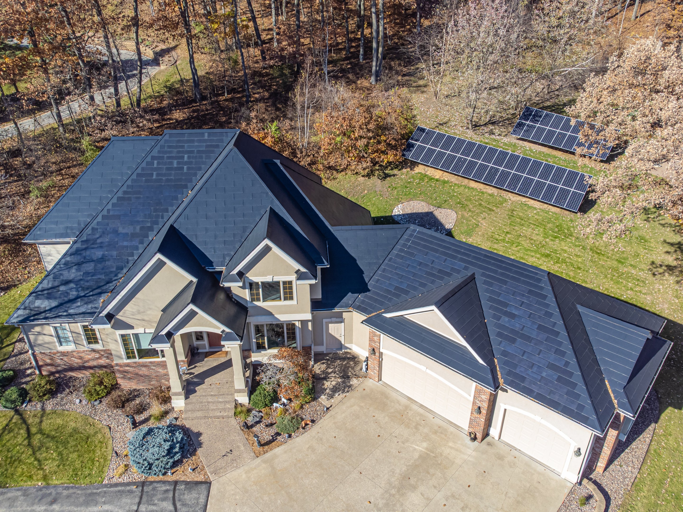 Luftaufnahme eines Hauses in North Carolina mit Solarpanelen auf dem Dach, umgeben von grünem Gras, Pflanzen und Bäumen.