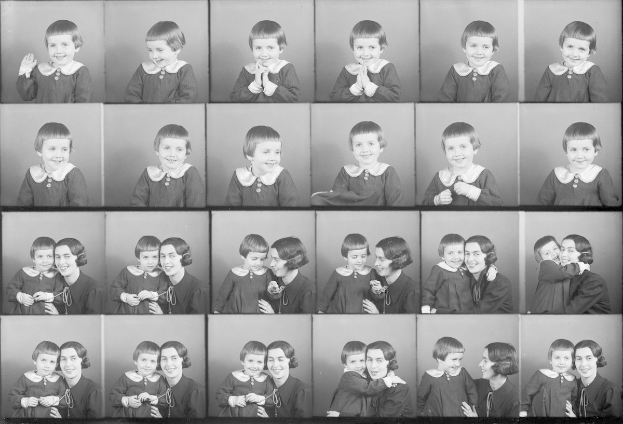 Schwarzes und weißes Foto einer Gruppe von Kindern mit einer Frau in der Mitte, die ein Baby liebevoll hält.