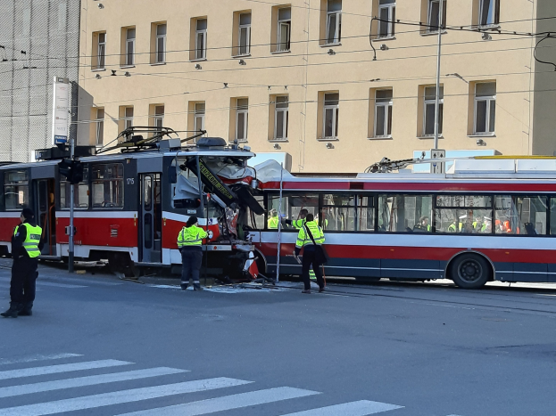 Rote und weiße Straßenbahn krachte auf der Straße mit Menschen in der Nähe und einem Gebäude im Hintergrund.