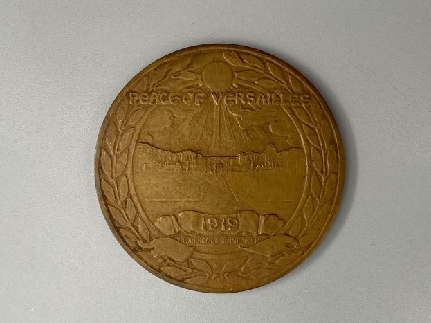 Eine Goldmedaille mit der Inschrift "Versailleser Frieden" auf einem weißen Hintergrund.