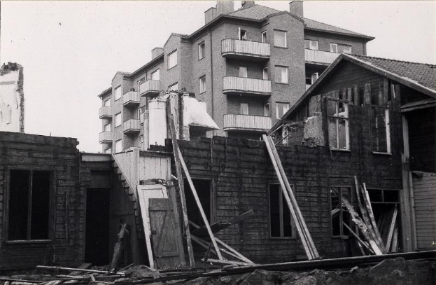 Ein Schwarzweißfoto der abgerissenen West End Apartments, mit Schutt auf dem Boden und dem Himmel im Hintergrund.